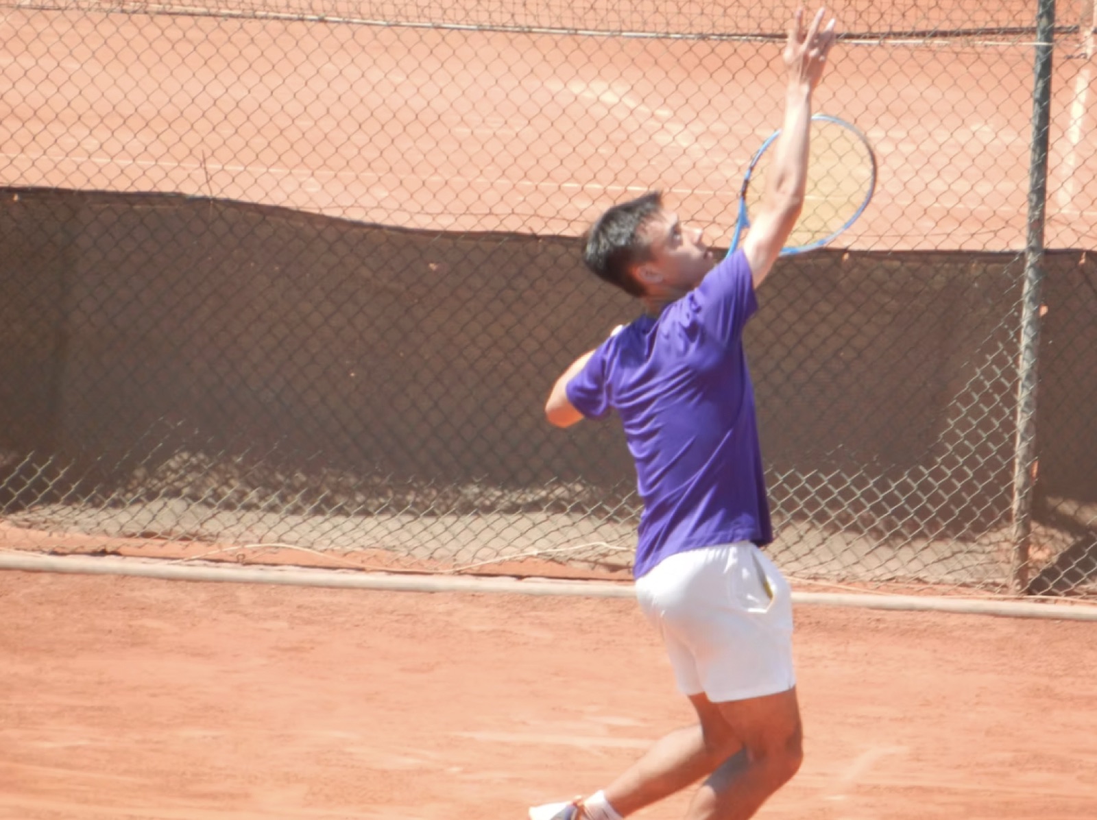 A player serving on a red clay court